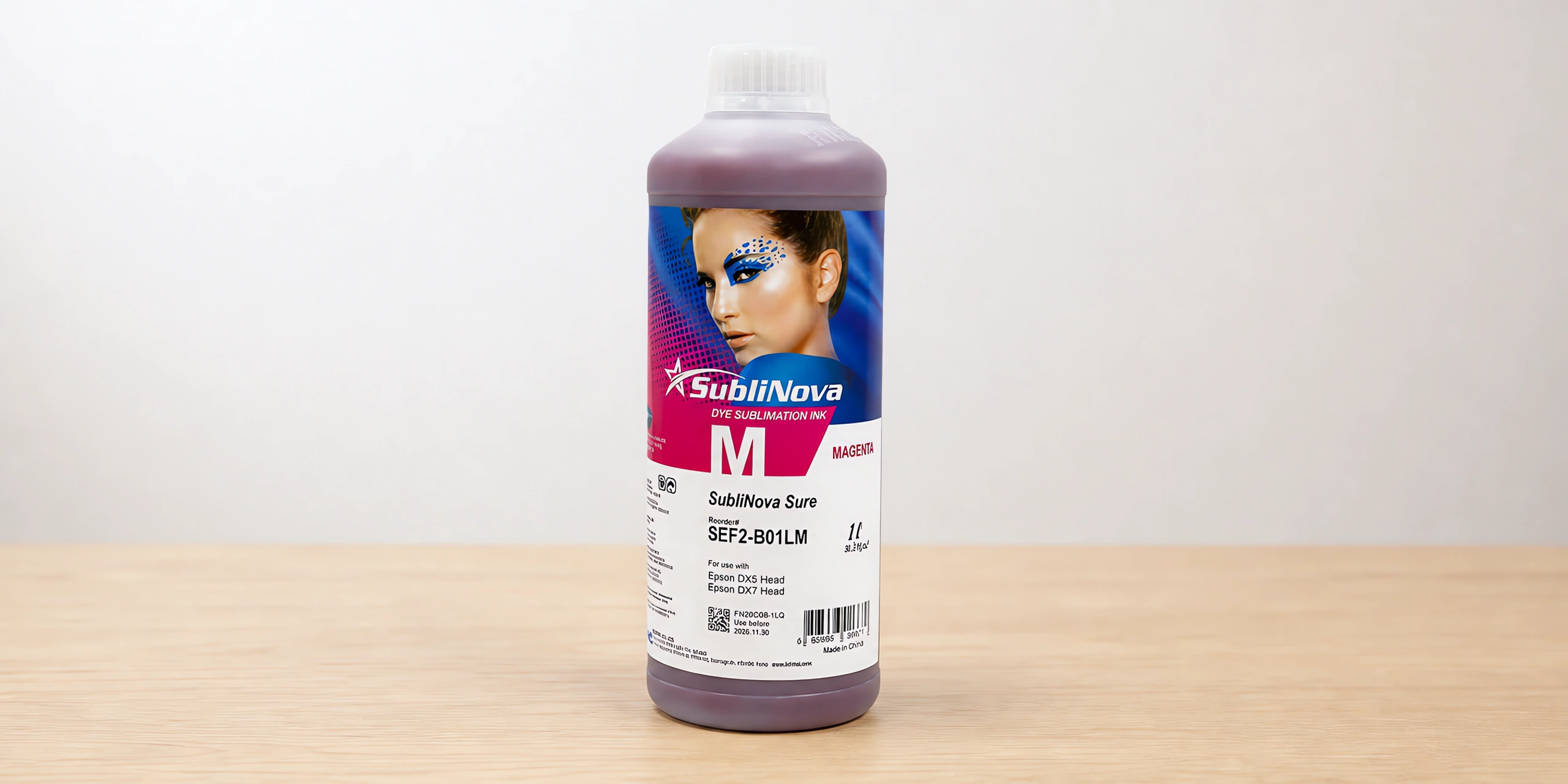 Tinta para sublimar de gran formato en su envase magenta, sobre la mesa de trabajo