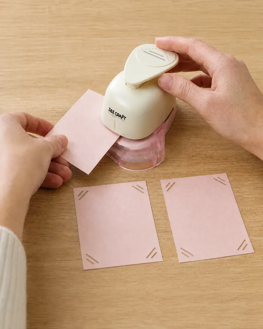 Manos usando el esquinero recto, con dos tarjetas ya caladas delante